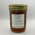 A glass jar of Caramel Apple Jam by BA Family Farms, filled with golden-brown jam and topped with a gold metal lid, set against a plain light gray background.