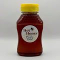 A bottle of BA Family Farms hot honey with a yellow cap and a round white label reading, shown on a light gray background.