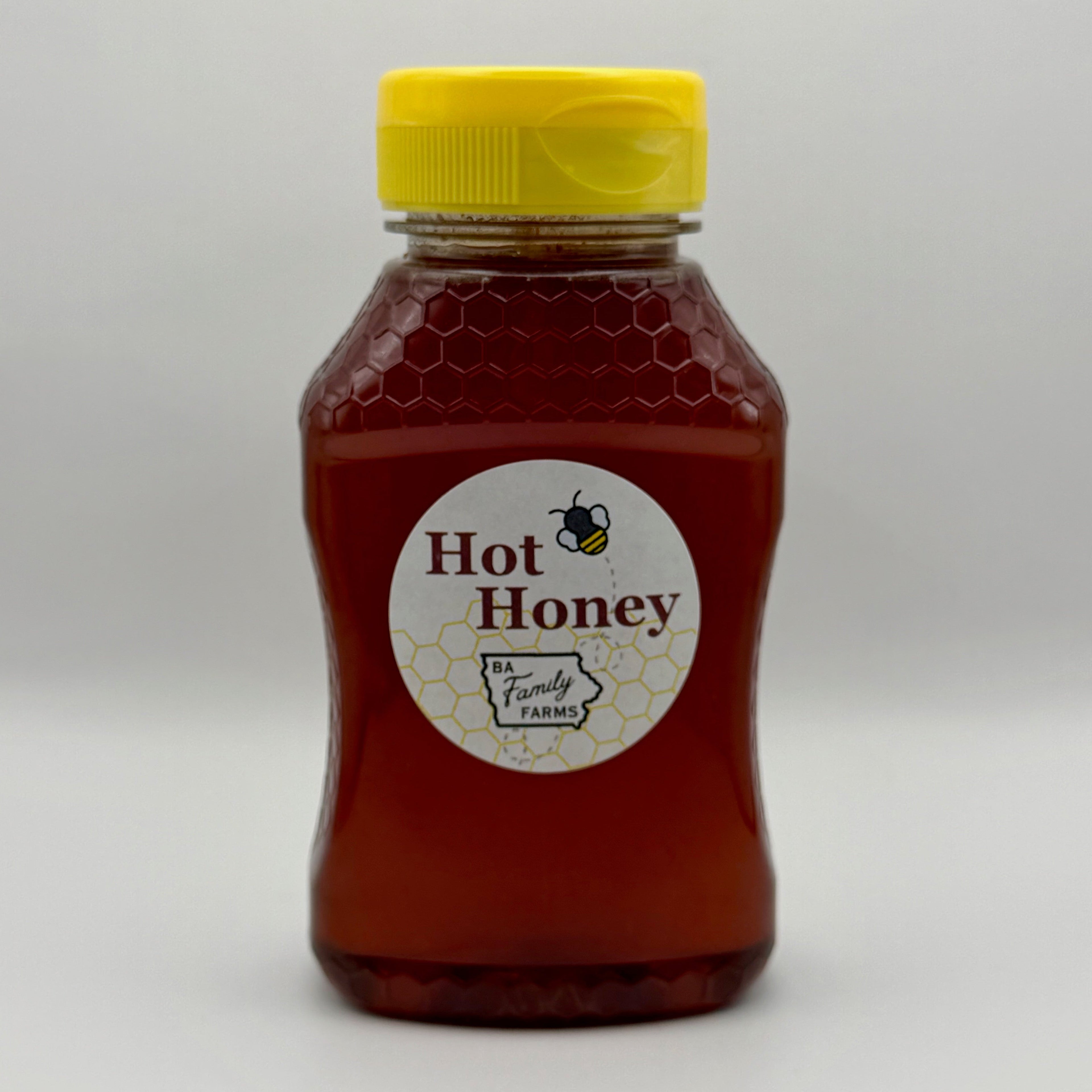 A bottle of BA Family Farms hot honey with a yellow cap and a round white label reading, shown on a light gray background.