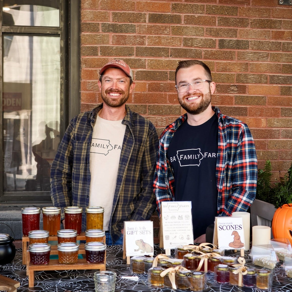 The two owners of BA Family Farms standing behind their booth at a local event with their farm and homemade products