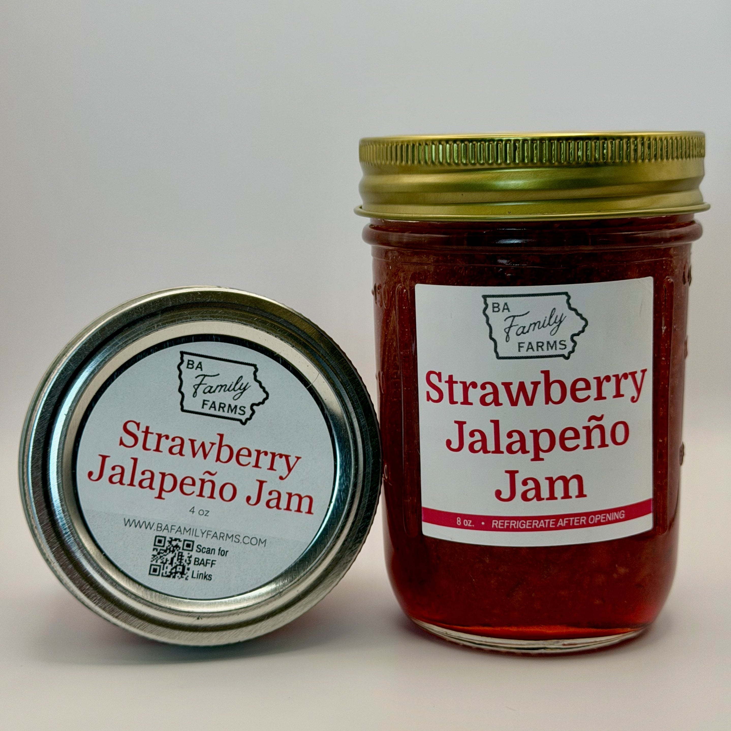 A jar of Strawberry Jalapeño Jam next to its lid, both showing the brand 'BA Family Farms' on a clean, light gray background.